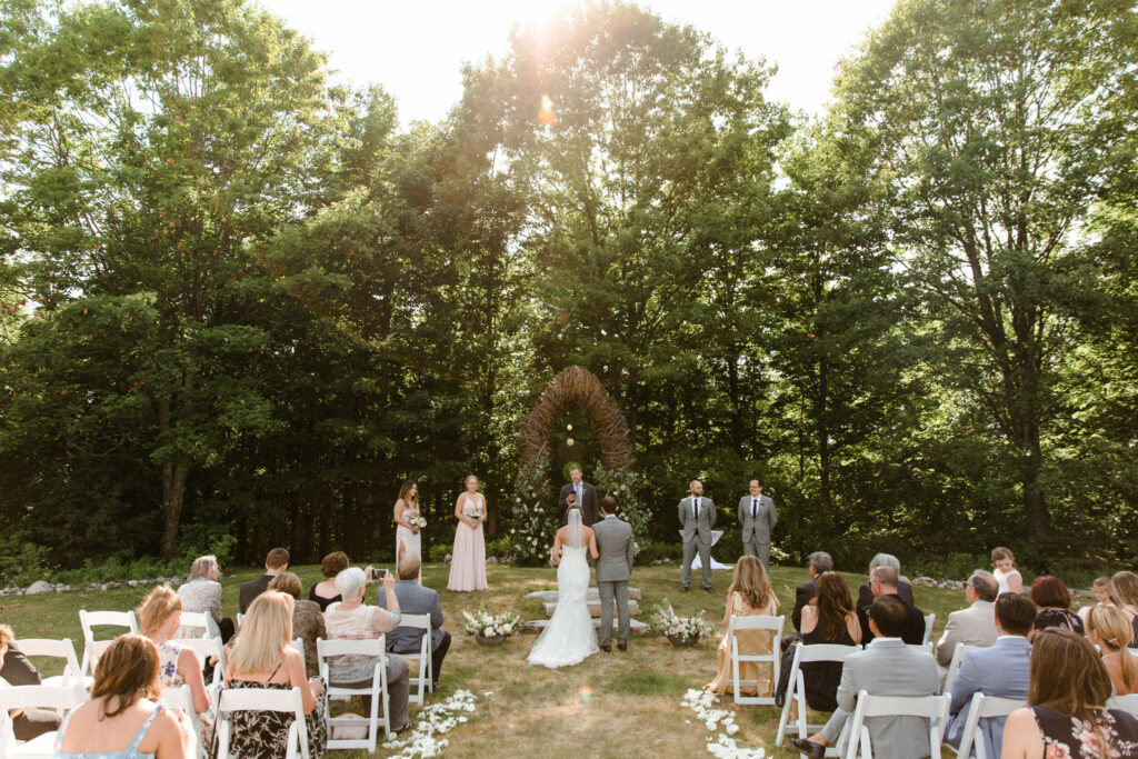 Dreamy wedding with forest backdrop and ceremony arch installation with foraged, local foliage.